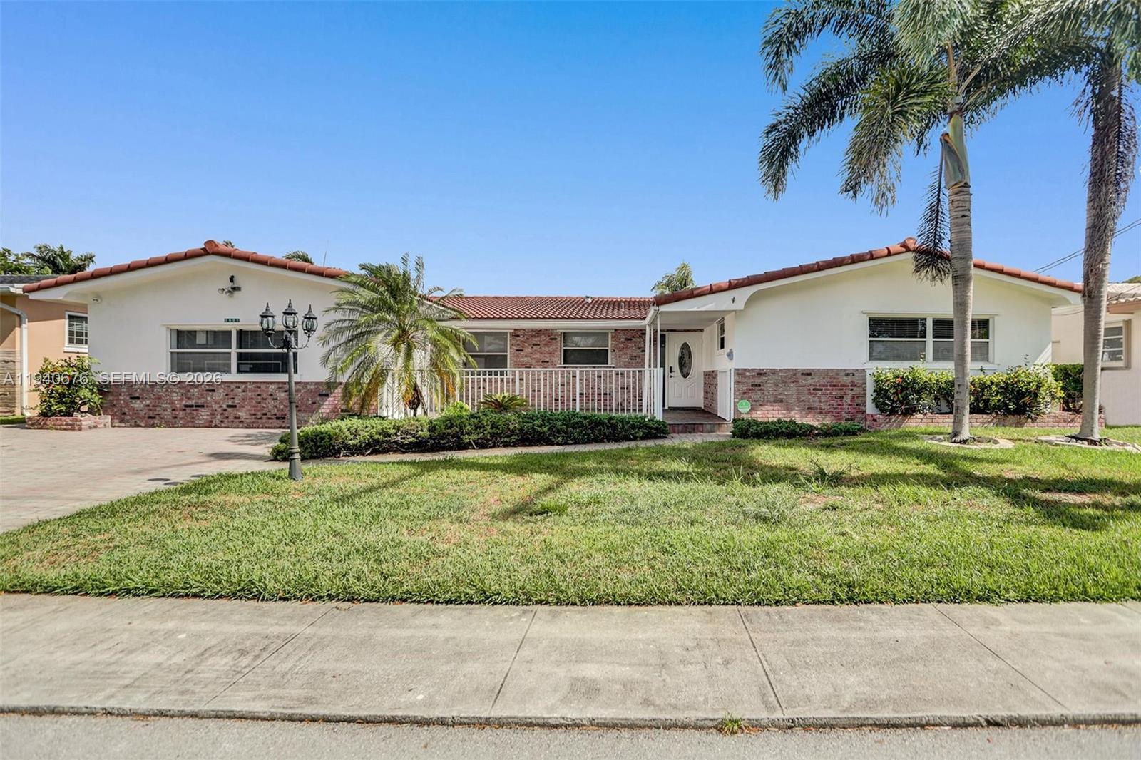 A single-story house with a brick and white facade, tile roof, and a front lawn — 2827 Arthur St, Hollywood FL 33020, HOLLYWOOD, FL