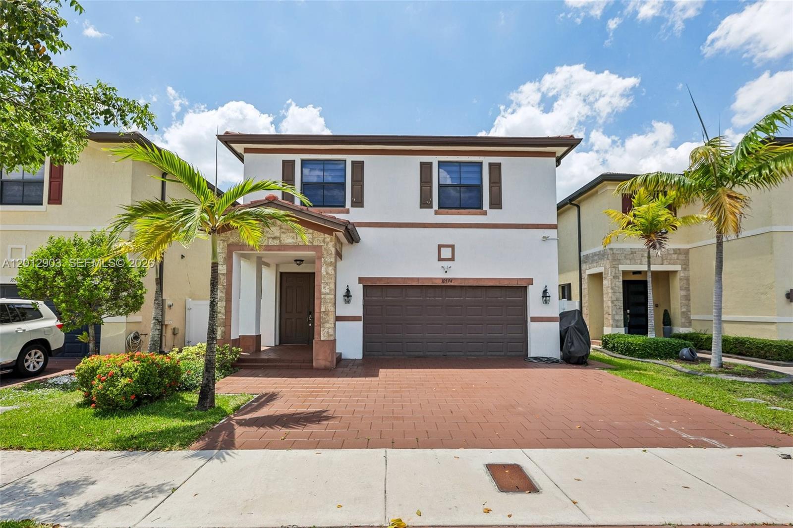 A two-story suburban house features a brown garage, a stone-accented entryway, and a paved driveway — 10594 W 35th Ln, Hialeah FL 33018, HIALEAH, FL