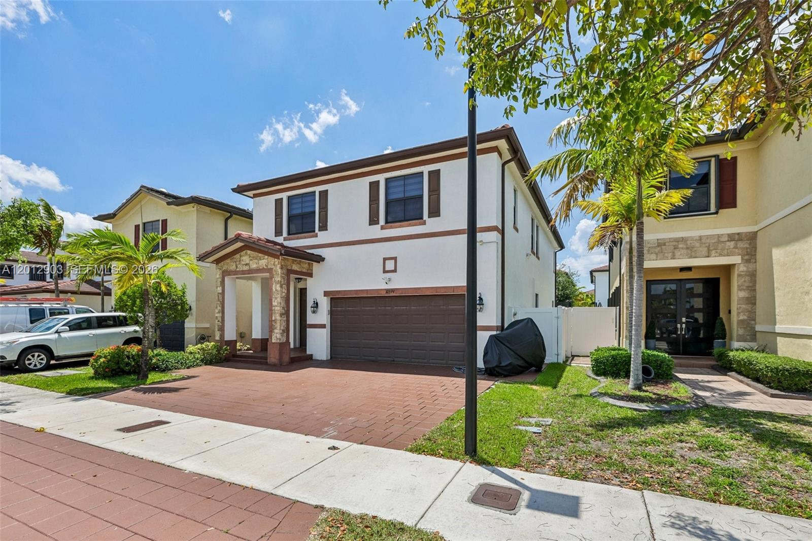 A two-story suburban house features a brown garage door, stone accents, and a paved driveway — 10594 W 35th Ln, Hialeah FL 33018, HIALEAH, FL