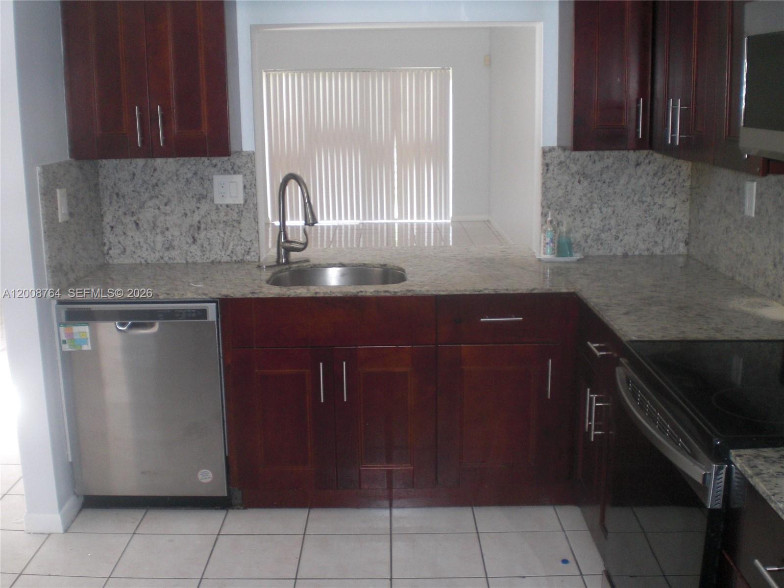 A kitchen features dark wood cabinets, granite countertops, stainless steel appliances, and white tile flooring — 962 NW 79th Ter, Plantation FL 33324, PLANTATION, FL