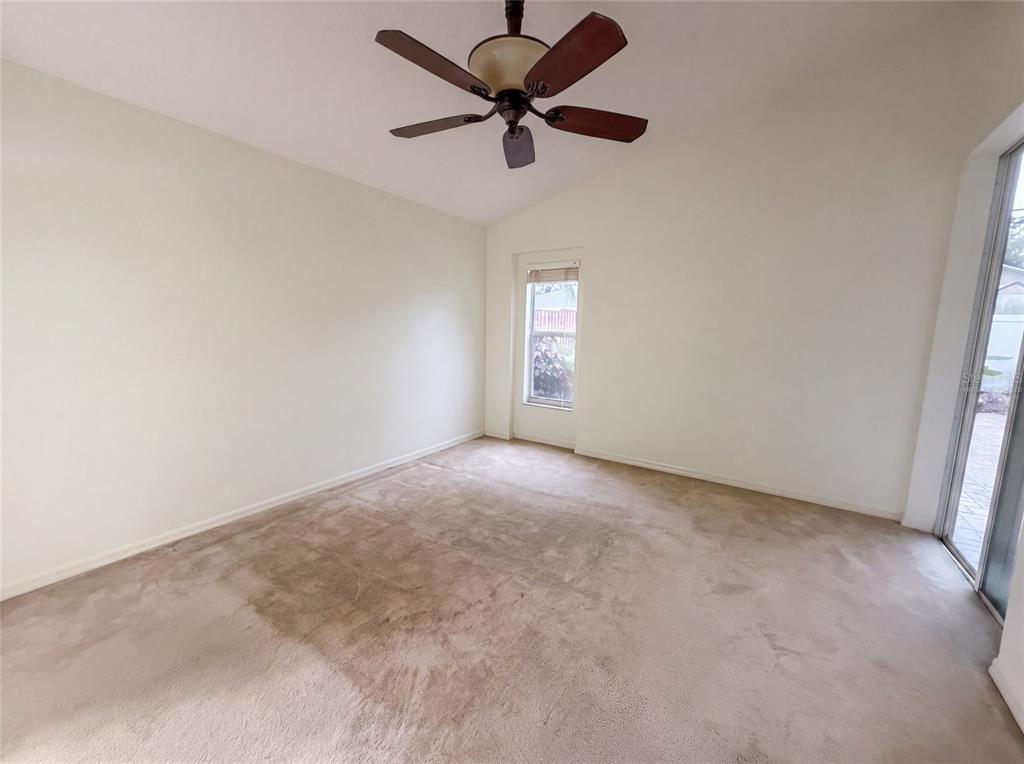 An empty room with beige carpet, white walls, a ceiling fan, and a sliding glass door — 6941 CROWN LAKE DRIVE, GIBSONTON, FL