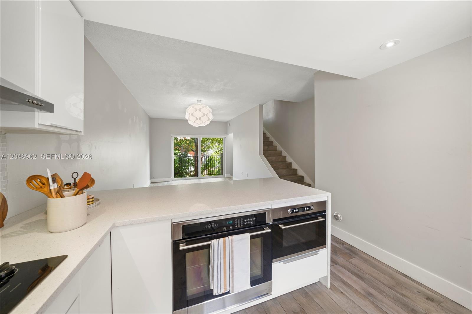 A kitchen island with built-in ovens overlooks a living area with stairs and a balcony — 1611 SW 2nd Ct # A104, Miami FL 33129, MIAMI, FL