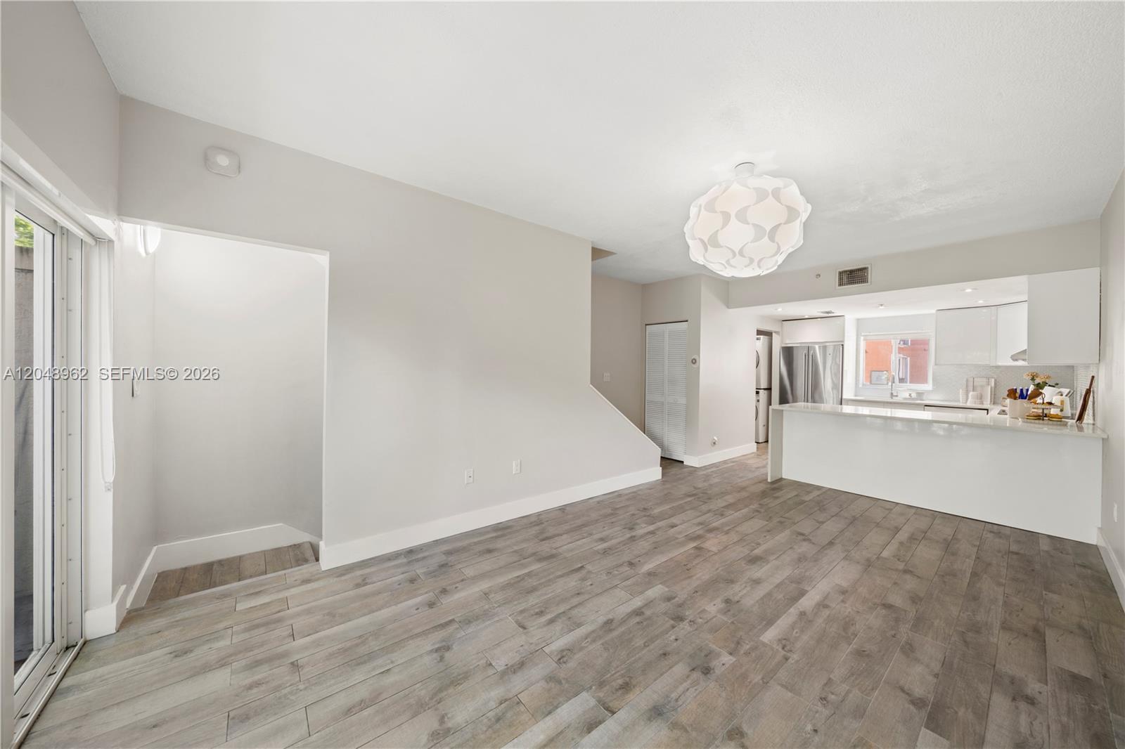 This open-concept living area features wood-look flooring, a modern pendant light, and a white kitchen — 1611 SW 2nd Ct # A104, Miami FL 33129, MIAMI, FL