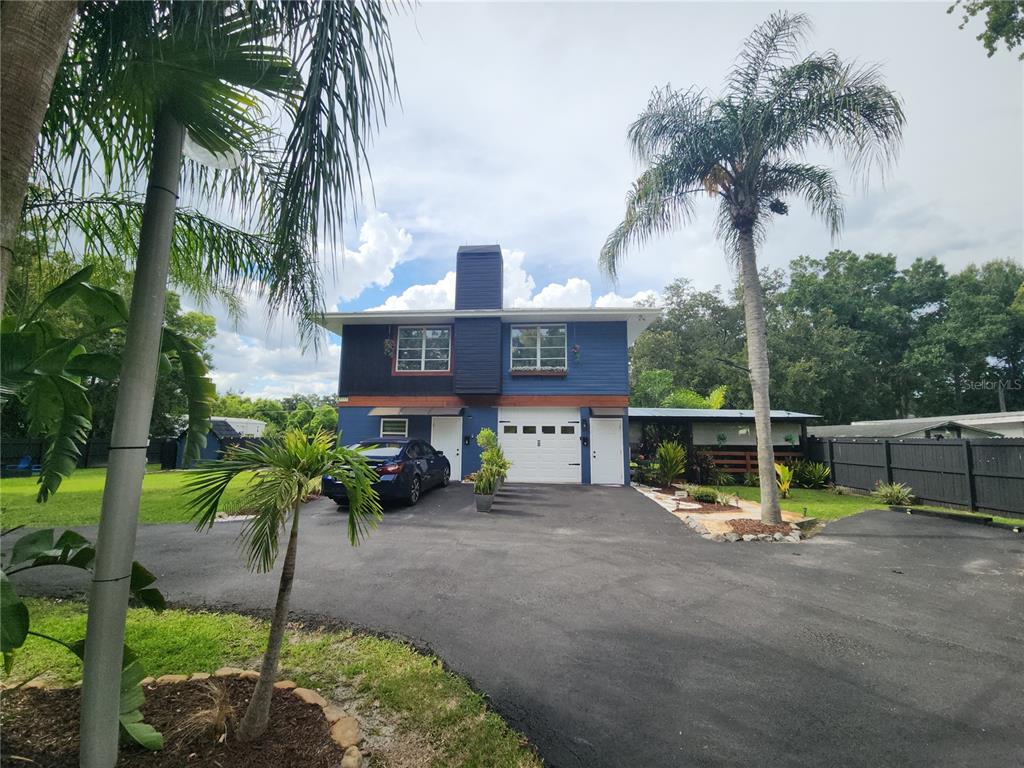 A two-story blue house with a central chimney, a garage, and a large paved driveway — 5113 PALMETTO ROAD, KISSIMMEE, FL