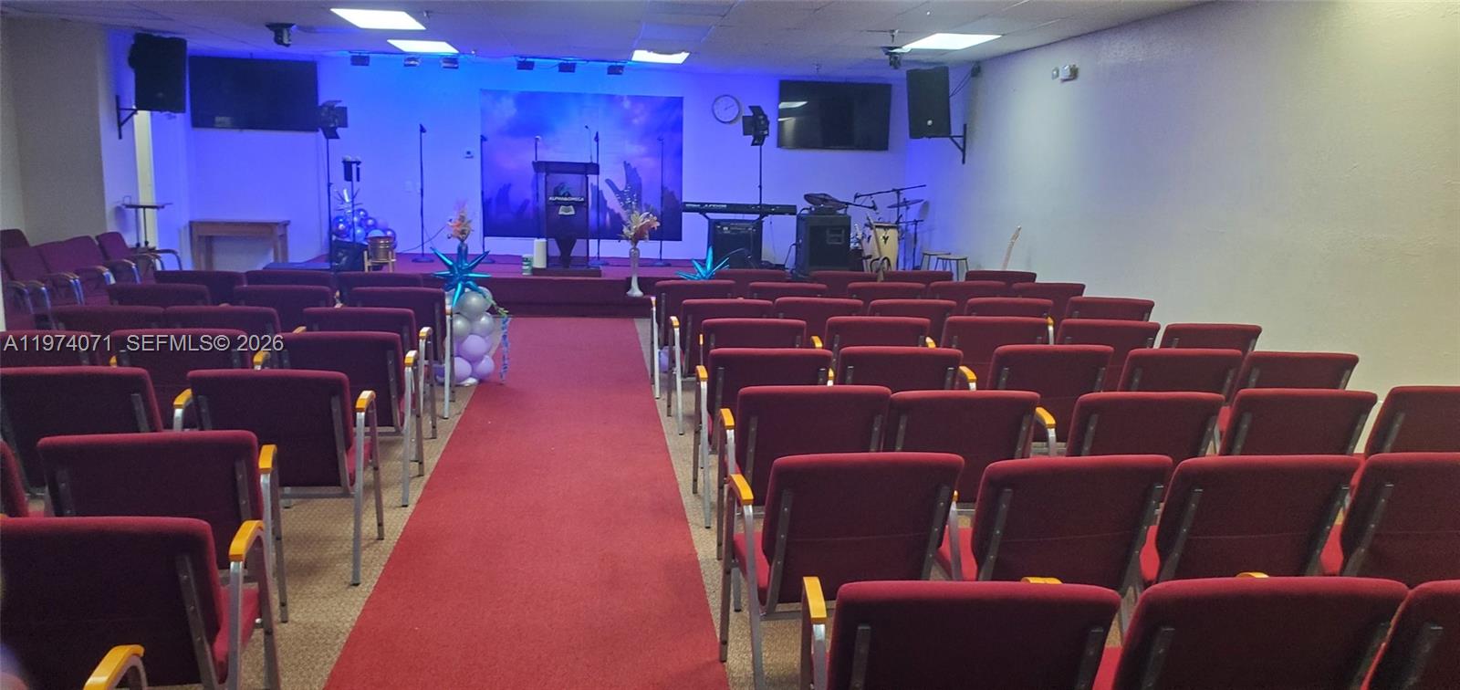 A church sanctuary features rows of maroon chairs facing a stage with a podium — 7894 W Sample Rd, Margate FL 33065, MARGATE, FL