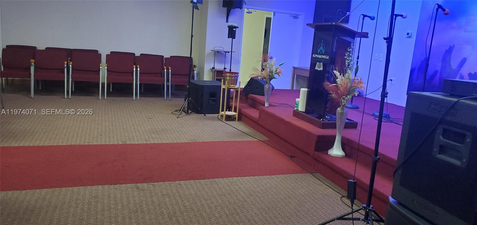 A church sanctuary features a carpeted stage, a podium, and rows of maroon chairs — 7894 W Sample Rd, Margate FL 33065, MARGATE, FL