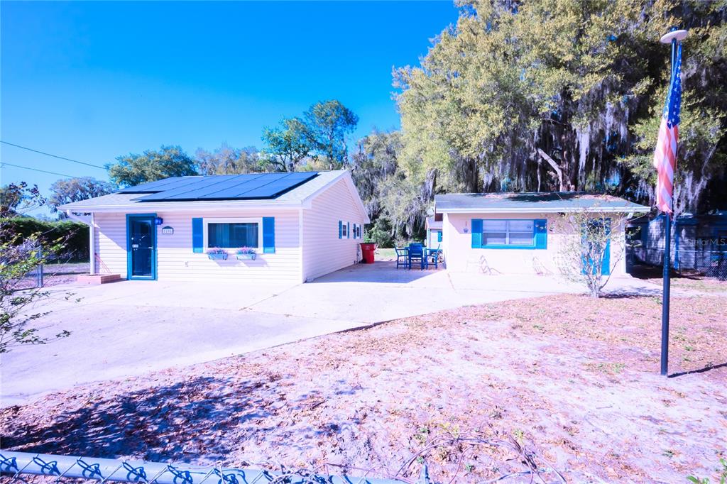 A single-story house with solar panels and a detached garage sits on a paved lot — 1198 CR 464, LAKE PANASOFFKEE, FL