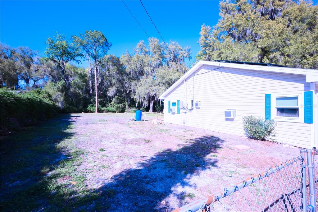 A side view of a house with light siding and blue shutters next to a yard — 1198 CR 464, LAKE PANASOFFKEE, FL
