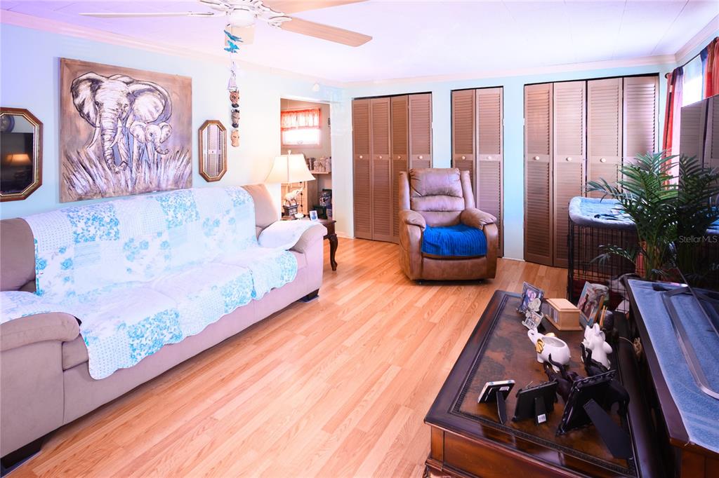 A living room features light wood flooring, a beige sofa with a quilt, and a recliner — 1198 CR 464, LAKE PANASOFFKEE, FL