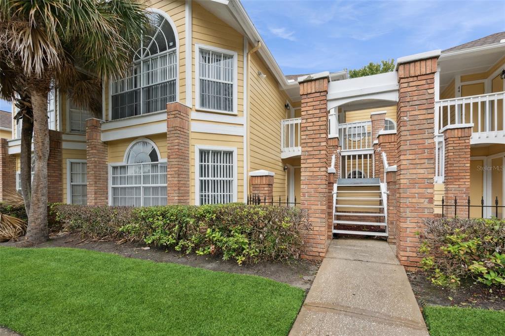 A two-story yellow building with brick columns and an exterior staircase leading to a balcony — 2442 SWEETWATER CLUB CIRCLE UNIT 41, KISSIMMEE, FL