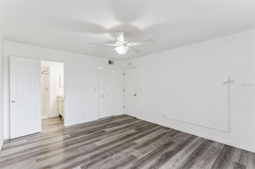 A bedroom with white walls, wood-look flooring, a ceiling fan, and an attached bathroom — 2442 SWEETWATER CLUB CIRCLE UNIT 41, KISSIMMEE, FL