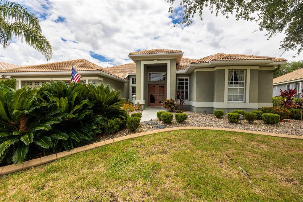 A single-story house with a tiled roof, tan stucco exterior, and a landscaped front yard — 6171 PALOMINO CIRCLE, BRADENTON, FL