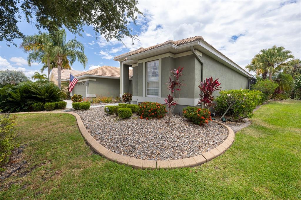A single-story house with a rock garden, manicured shrubs, and a green lawn — 6171 PALOMINO CIRCLE, BRADENTON, FL