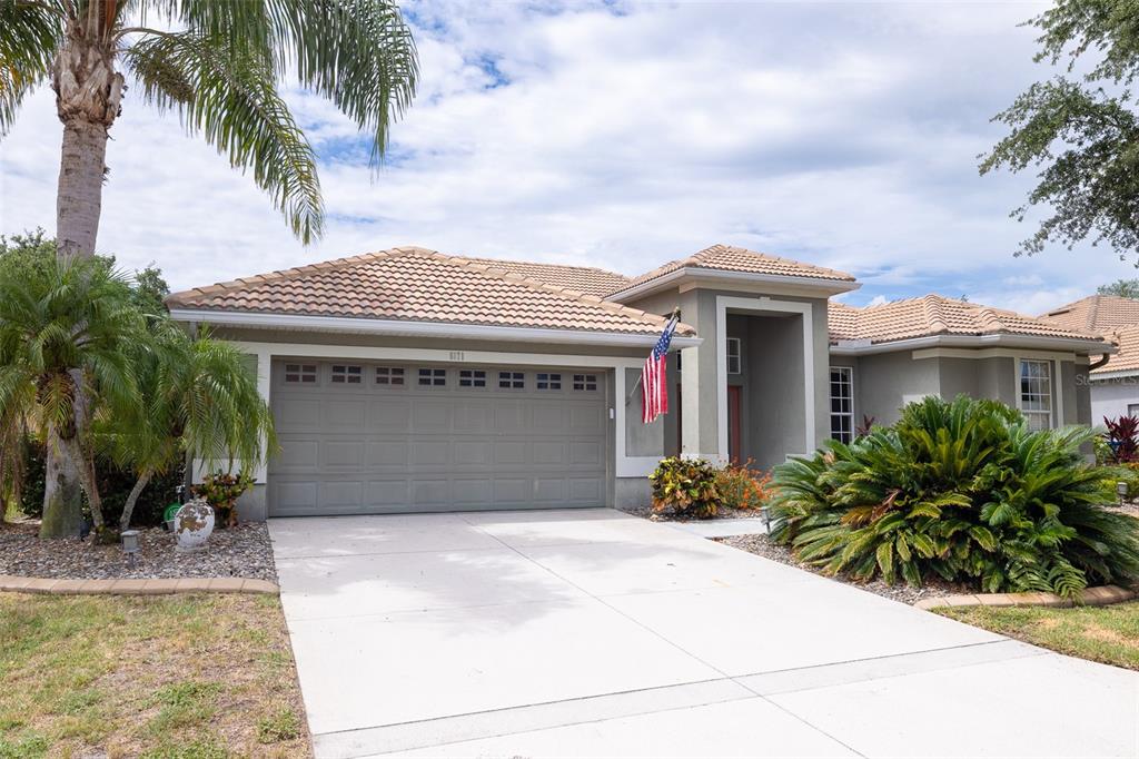 A single-story house with a beige stucco exterior, a tile roof, and a two-car garage — 6171 PALOMINO CIRCLE, BRADENTON, FL