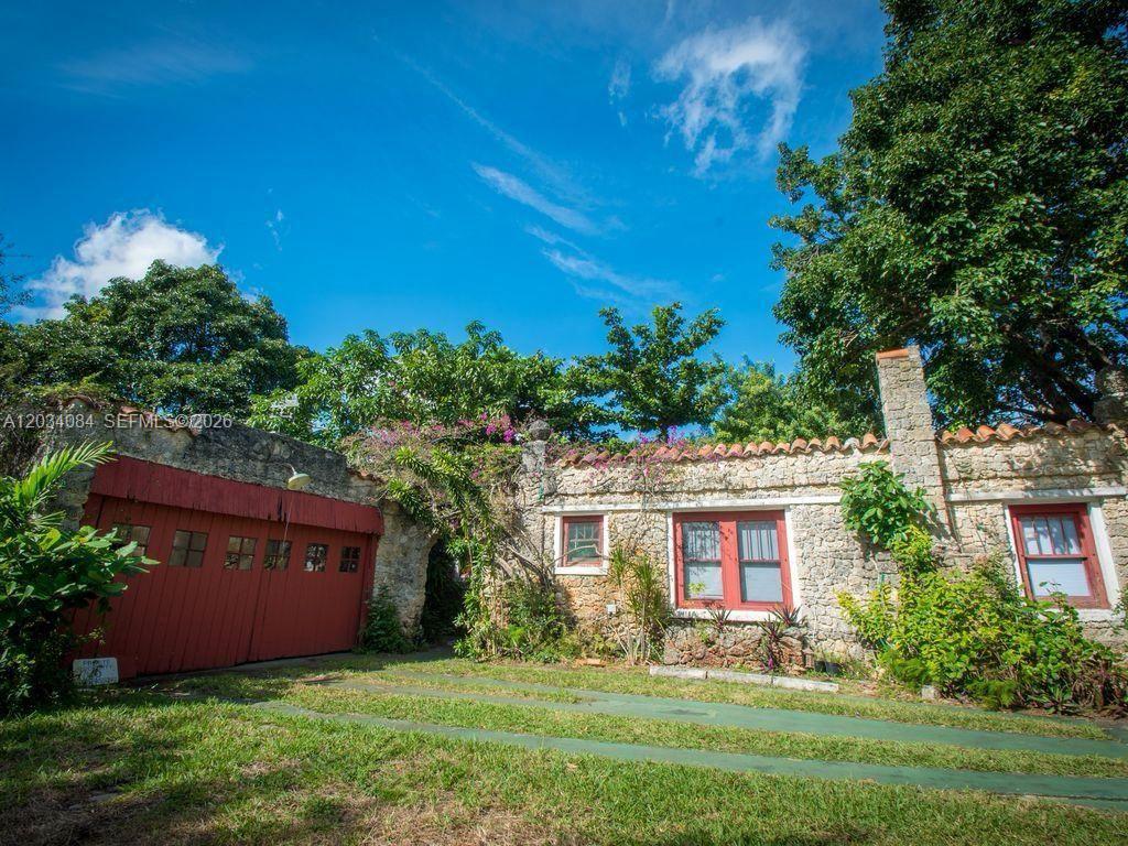 A stone house with a red garage door and a grass-paved driveway — 8238 NE 9th Ave, Miami FL 33138, MIAMI, FL