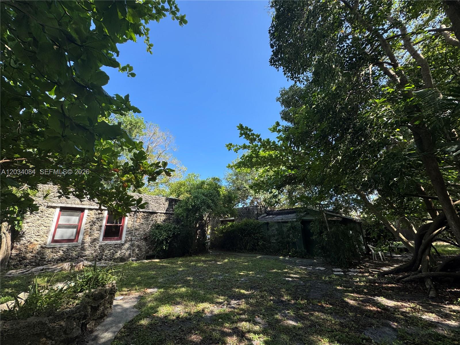 The exterior of a stone building features two windows with red frames and white trim — 8238 NE 9th Ave, Miami FL 33138, MIAMI, FL