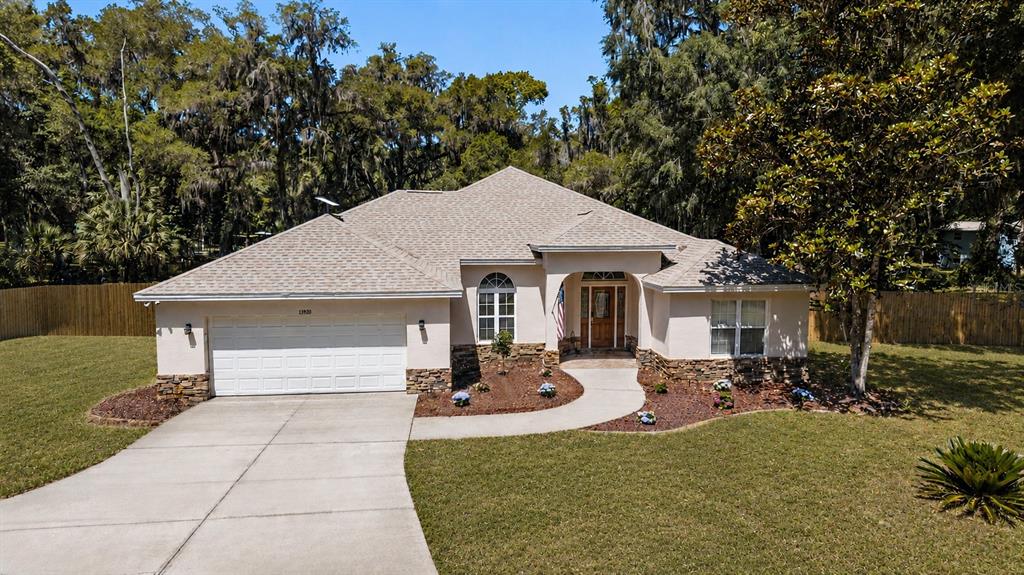 A single-story house with a white garage, stone accents, and a concrete driveway — 13920 NE 38TH AVENUE, ANTHONY, FL