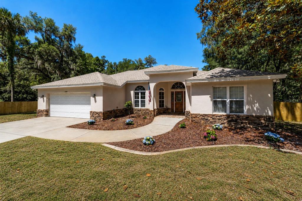 A single-story house with a white stucco exterior, stone accents, and a two-car garage — 13920 NE 38TH AVENUE, ANTHONY, FL