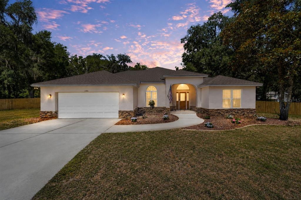 A single-story house with a white stucco exterior, stone accents, and a two-car garage — 13920 NE 38TH AVENUE, ANTHONY, FL