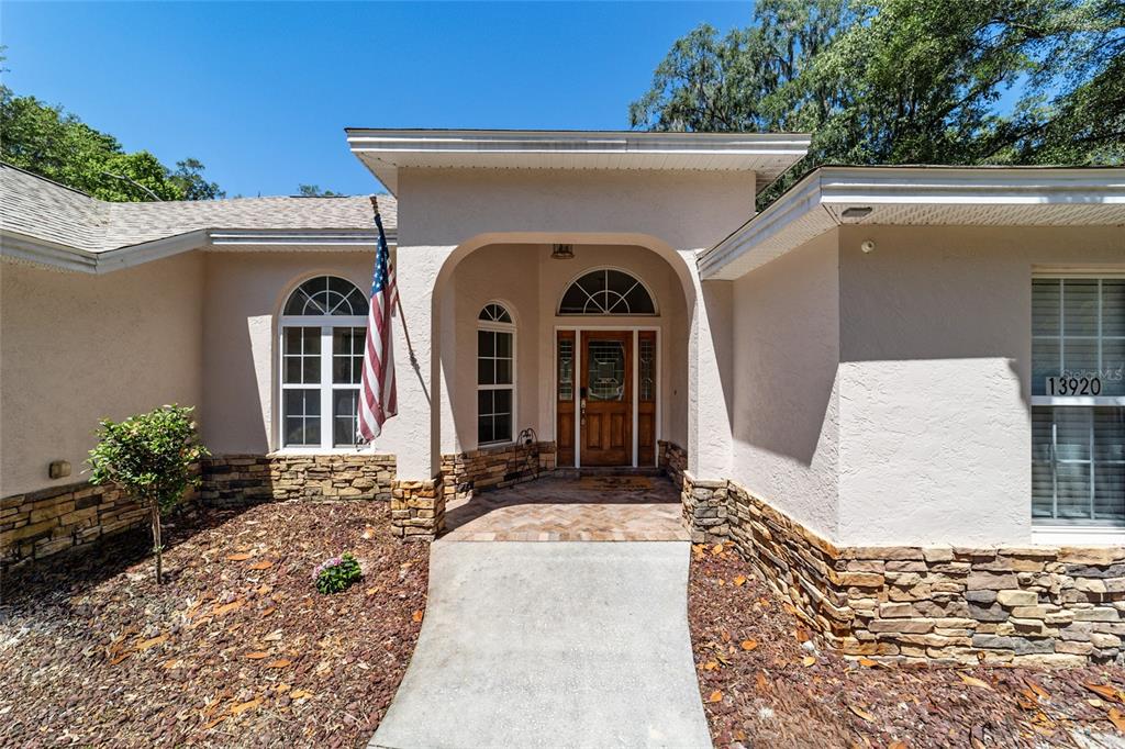 The exterior of a house features a stone-accented facade, a covered entryway, and an American flag — 13920 NE 38TH AVENUE, ANTHONY, FL