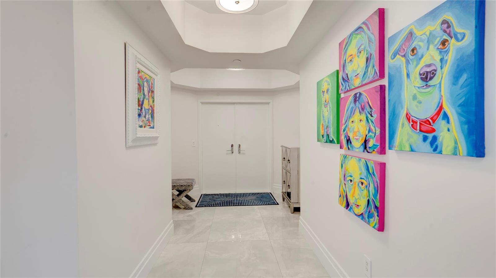 A bright hallway features white walls, tile flooring, a tray ceiling, and colorful wall art — 1440 S Ocean Boulevard # c, Pompano Beach FL 33062, POMPANO BEACH, FL