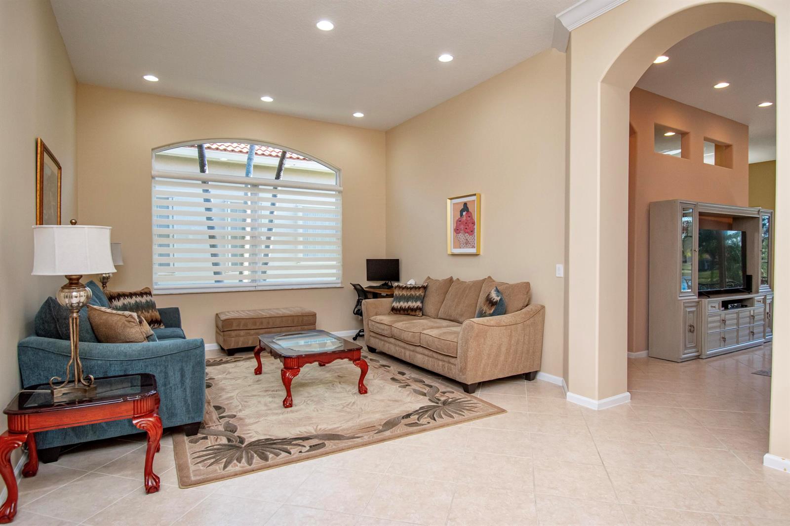 A living room features a tan sofa, blue armchair, coffee table, and an arched window — 7080 Demedici Circle # 7080, Delray Beach FL 33446, DELRAY BEACH, FL