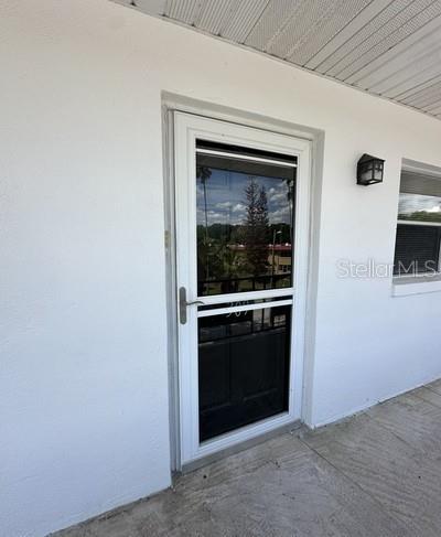 A white exterior door with a glass storm door is set into a white wall — 100 EL CAMINO DR UNIT 309, WINTER HAVEN, FL