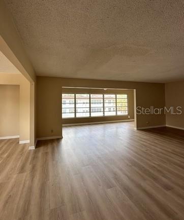 An empty living room with light wood-look flooring and a large window overlooking a building — 100 EL CAMINO DR UNIT 309, WINTER HAVEN, FL