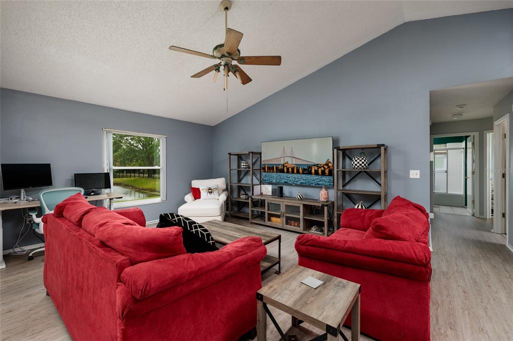 A living room features two red sofas, a television, shelving, and a ceiling fan — 502 36TH STREET W, PALMETTO, FL
