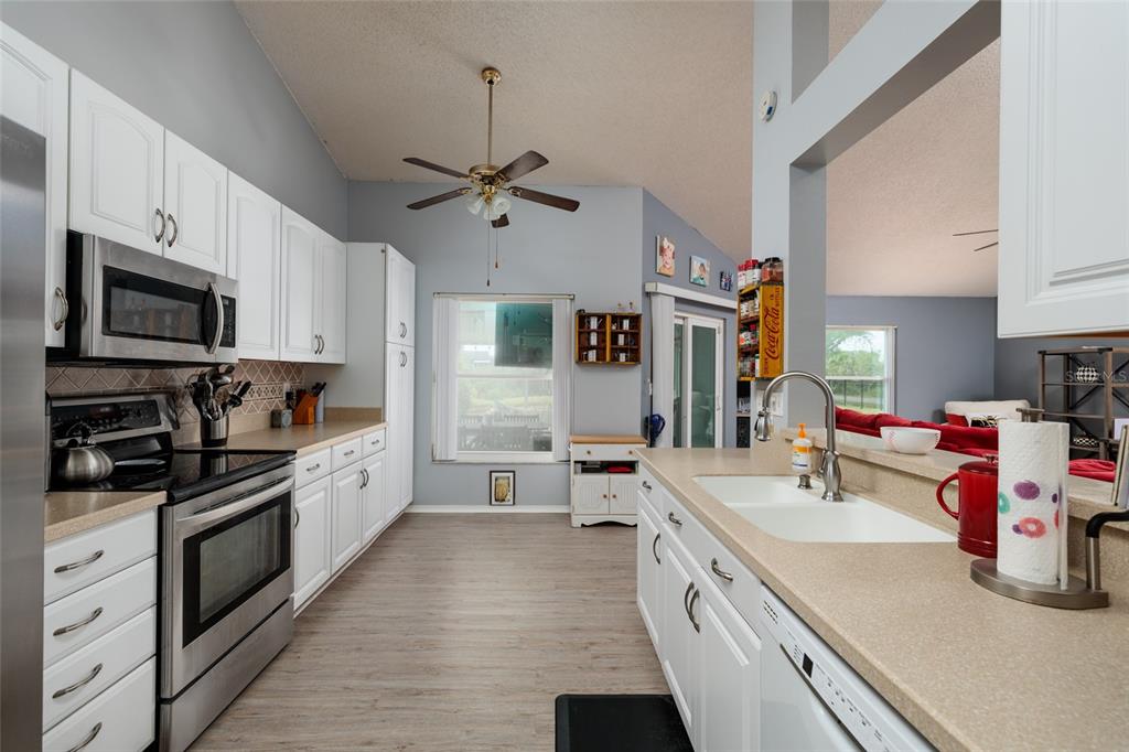 A kitchen features white cabinets, stainless steel appliances, a center island, and light-colored countertops — 502 36TH STREET W, PALMETTO, FL