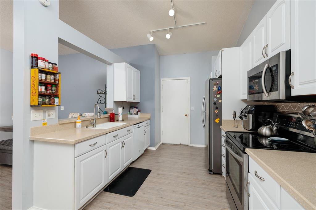 A kitchen features white cabinets, stainless steel appliances, a beige countertop, and a spice rack — 502 36TH STREET W, PALMETTO, FL