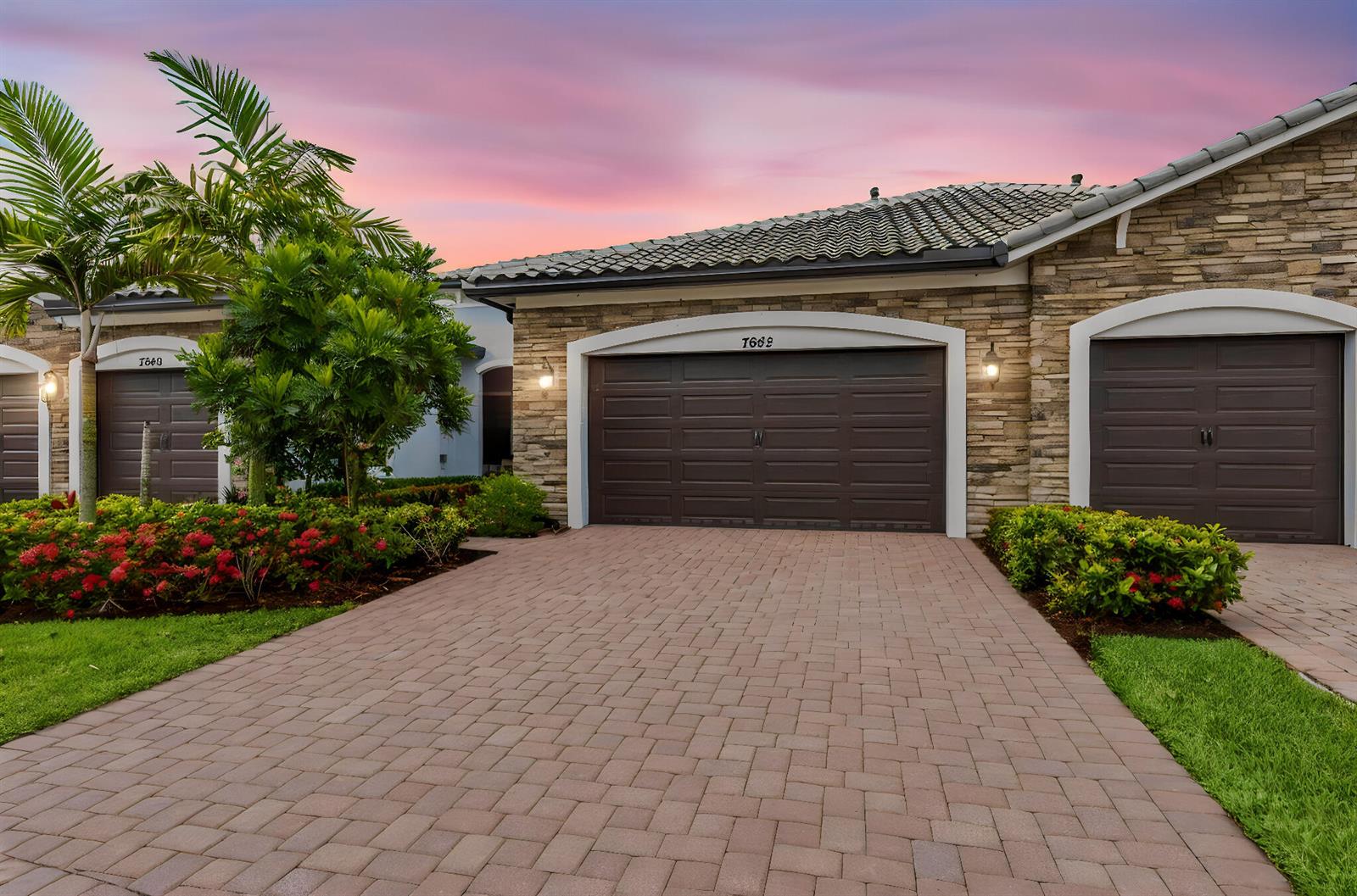 The exterior of a house with a stone facade, two garage doors, and a paved driveway — 7642 N Blue Spring Drive, Parkland FL 33067, PARKLAND, FL