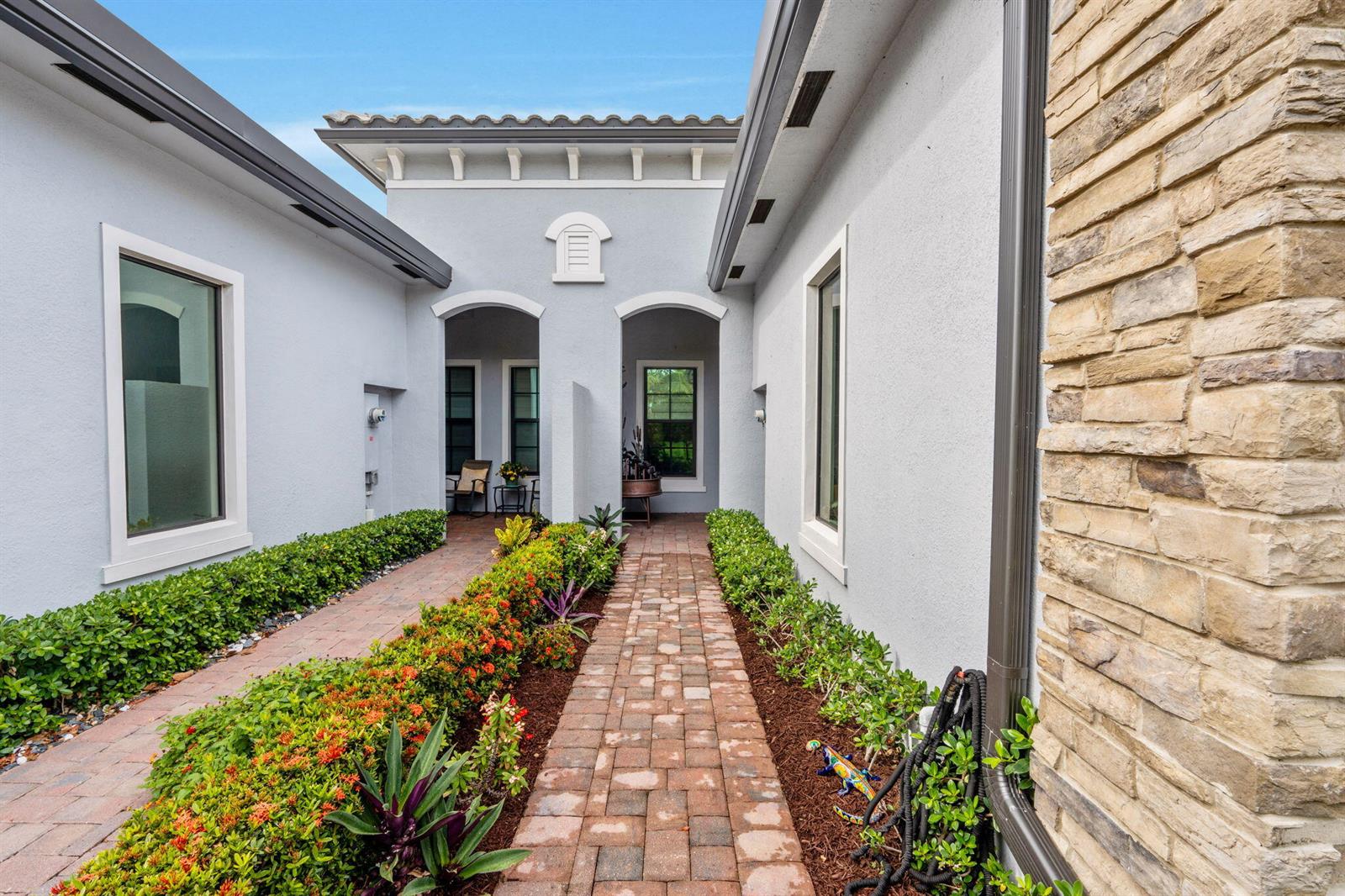 A brick walkway leads to a covered entryway between two light-colored stucco building wings — 7642 N Blue Spring Drive, Parkland FL 33067, PARKLAND, FL