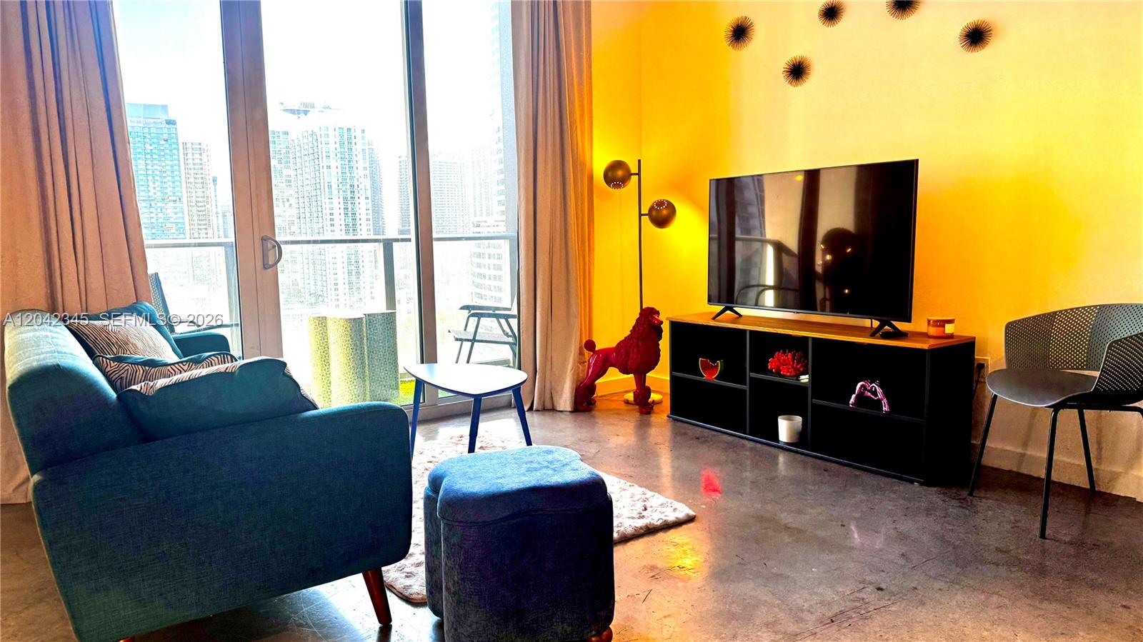 A living room features a blue sofa, a television on a black stand, and a balcony — 151 SE 1st St # 2205, Miami FL 33131, MIAMI, FL