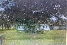 A light-colored single-story house sits behind a large tree on a grassy lot — 4545 WINDEE AVENUE, LAKELAND, FL