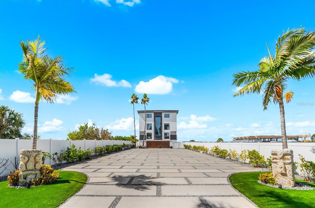 A modern multi-story house sits at the end of a long, paved driveway with palm trees — 811 N SHORE DRIVE, ANNA MARIA, FL