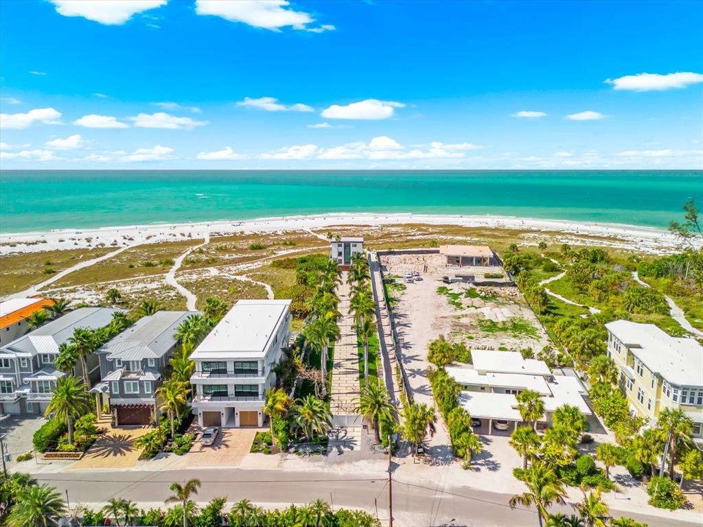 An aerial view shows a beachfront property with a modern house and an adjacent vacant lot — 811 N SHORE DRIVE, ANNA MARIA, FL