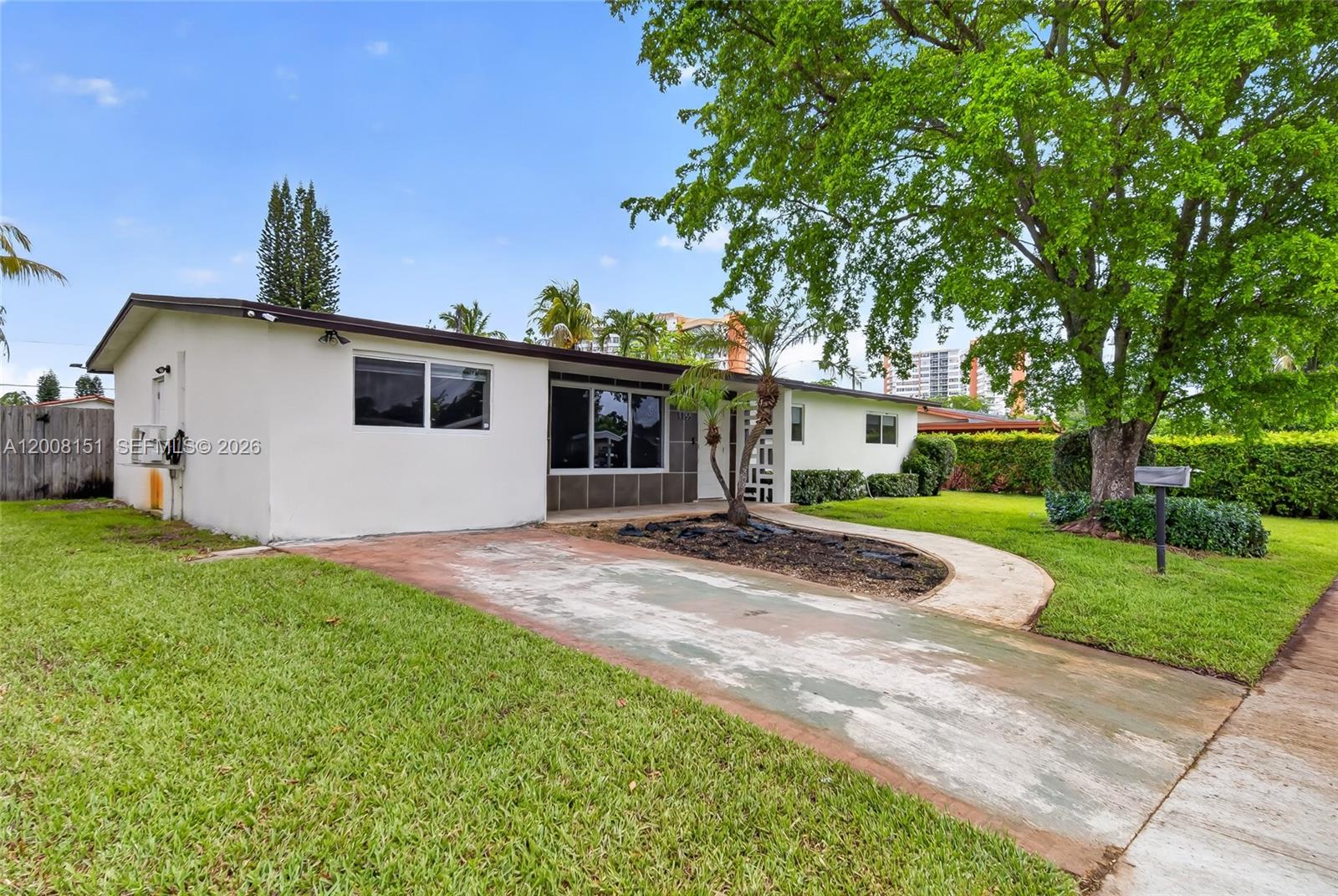 A single-story white house with a concrete driveway and a large tree in the yard — 1155 NE 184th St, Miami FL 33179, MIAMI, FL