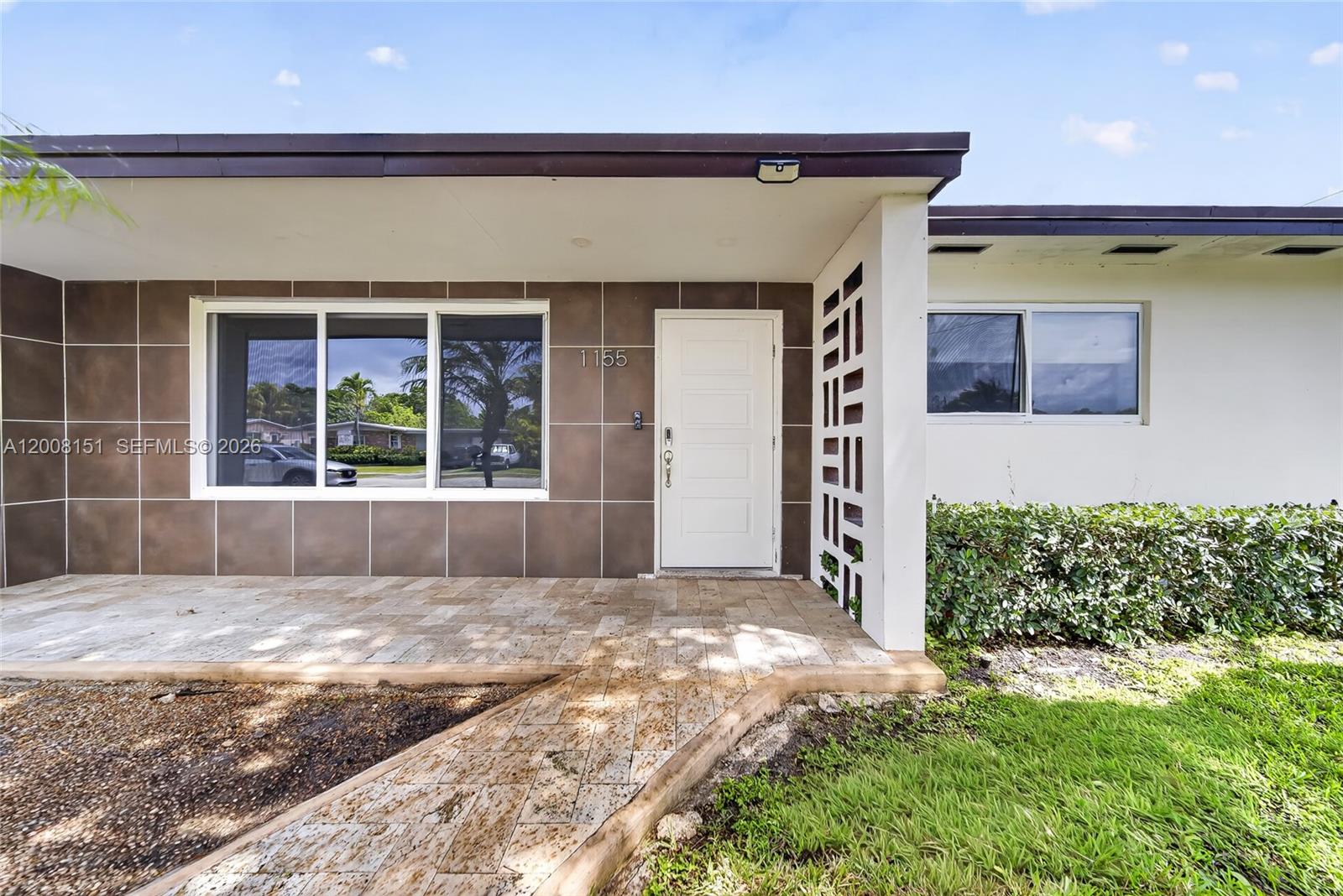 The exterior of a house features a tiled porch, a white front door, and decorative screen blocks — 1155 NE 184th St, Miami FL 33179, MIAMI, FL