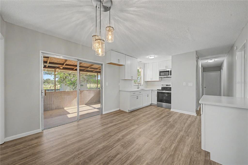 A kitchen and dining area with white cabinets, stainless steel appliances, and wood-look flooring — 4717 HOWARD STREET, SEBRING, FL