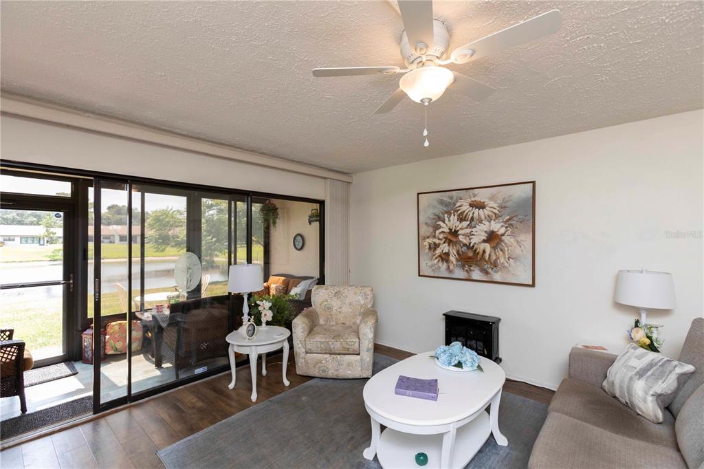 A living room features a ceiling fan, a fireplace, and sliding doors opening to a patio — 7614 RADCLIFFE CIRCLE UNIT B109, PORT RICHEY, FL