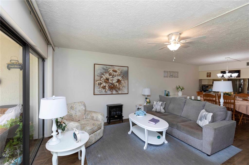 A living room with a grey sofa, floral armchair, white coffee table, and ceiling fan — 7614 RADCLIFFE CIRCLE UNIT B109, PORT RICHEY, FL