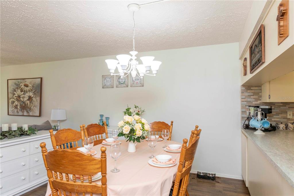 A dining room features a wooden table with six chairs, a chandelier, and a sideboard — 7614 RADCLIFFE CIRCLE UNIT B109, PORT RICHEY, FL