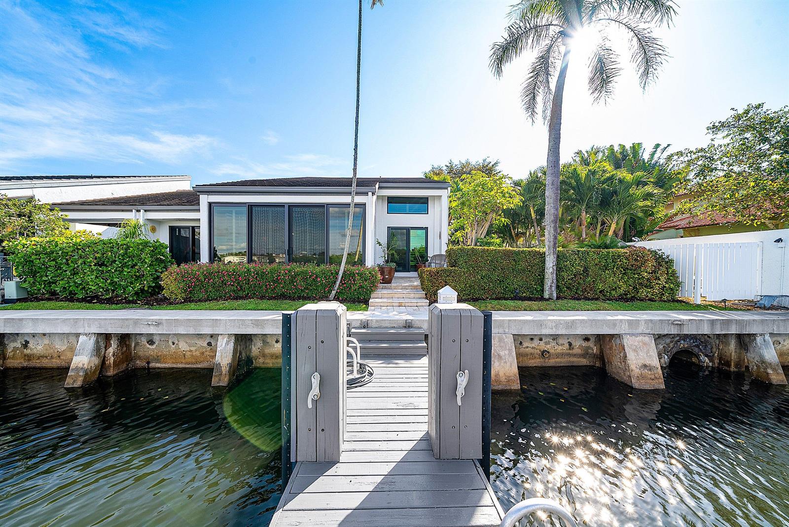 A waterfront house with a private dock, large windows, and lush landscaping under a sunny sky — 6110 N Ocean Boulevard # 40, Ocean Ridge FL 33435, OCEAN RIDGE, FL