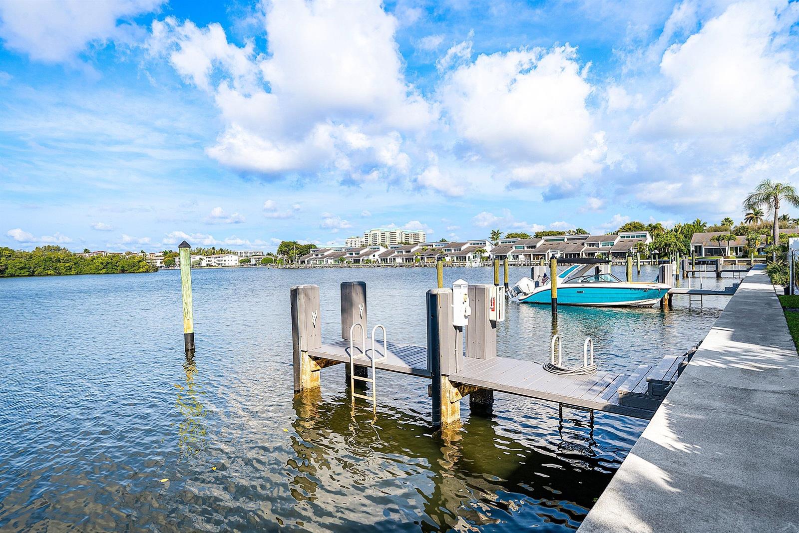 A wooden boat dock extends into a calm waterway with a blue boat moored nearby — 6110 N Ocean Boulevard # 40, Ocean Ridge FL 33435, OCEAN RIDGE, FL