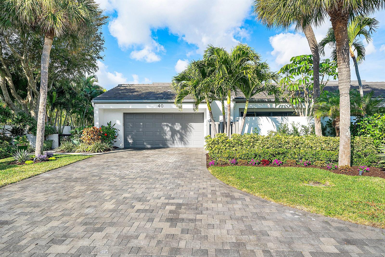 A paved driveway leads to a one-car garage at a white house with palm trees — 6110 N Ocean Boulevard # 40, Ocean Ridge FL 33435, OCEAN RIDGE, FL