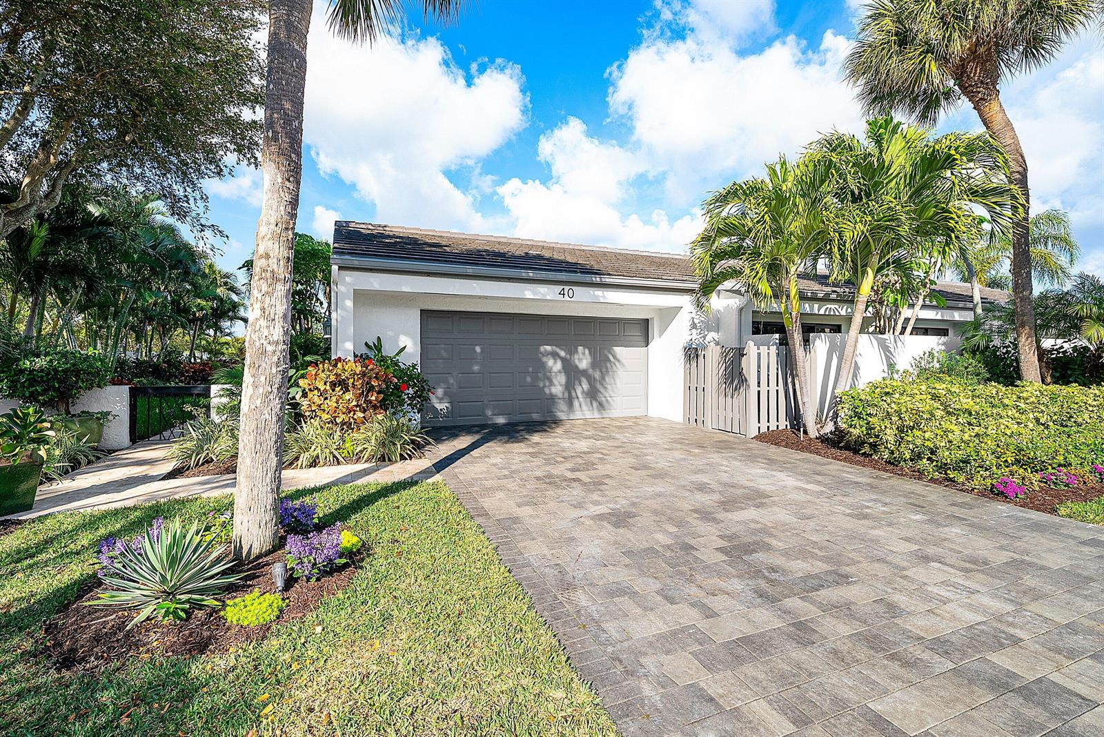 A single-story house with a gray garage door, paved driveway, and palm trees — 6110 N Ocean Boulevard # 40, Ocean Ridge FL 33435, OCEAN RIDGE, FL