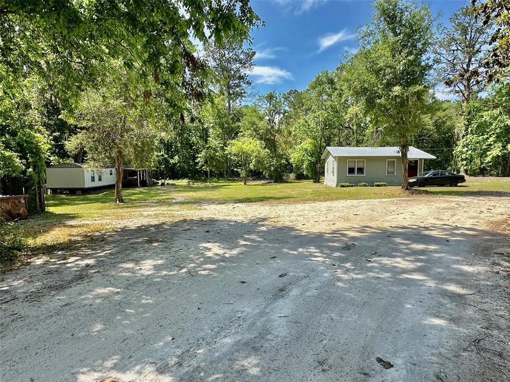 A dirt driveway leads to a small house and a mobile home on a wooded lot — 12100 NW US HIGHWAY 441, ALACHUA, FL