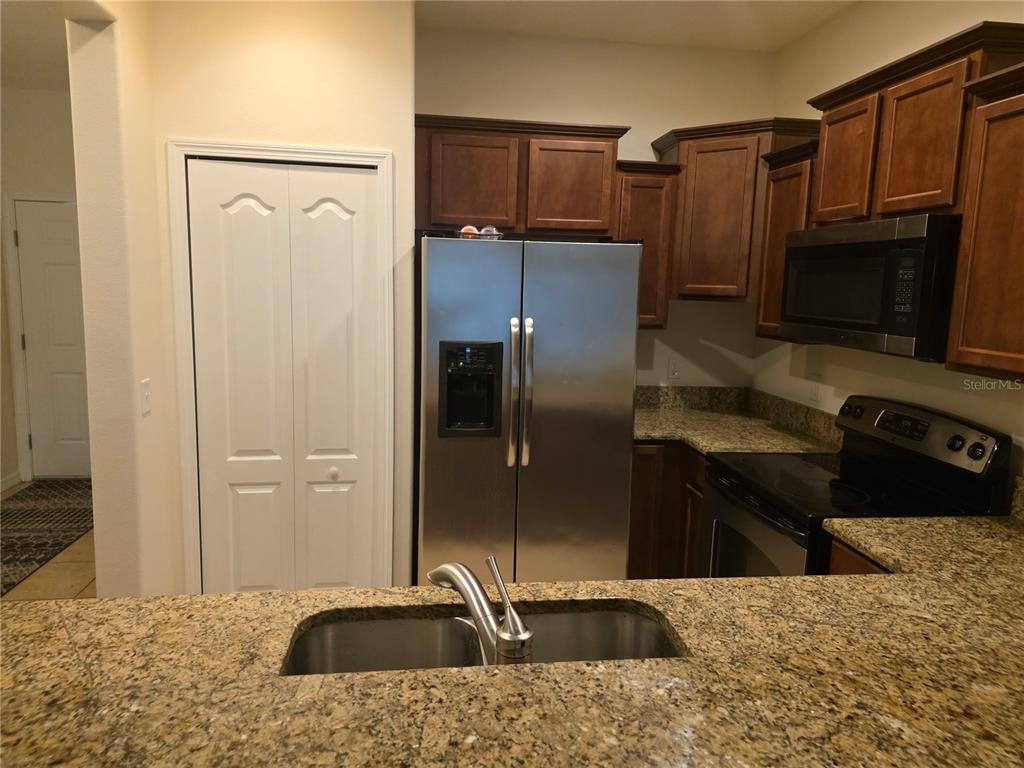 A kitchen features dark wood cabinets, granite countertops, stainless steel appliances, and a double sink — 3158 RODRICK CIRCLE UNIT 3158, ORLANDO, FL