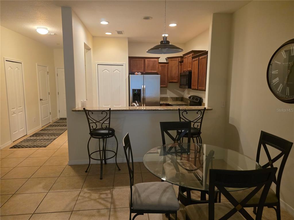 A kitchen with dark wood cabinets, granite countertops, and a breakfast bar with two stools — 3158 RODRICK CIRCLE UNIT 3158, ORLANDO, FL